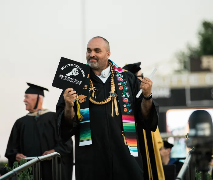 Butte College 2025 Commencement: Automotive Program graduate proudly displays his degree to the crowd