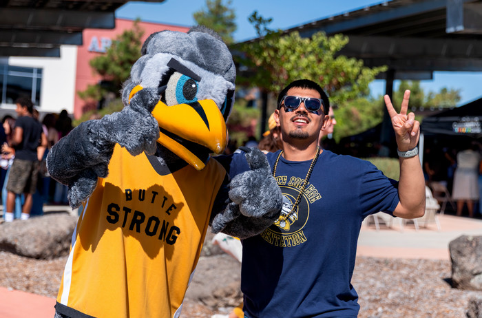 student-flashes-peace-sign-while-posing-with-dash-mascot-at-roadrunner-rush-campus-event
