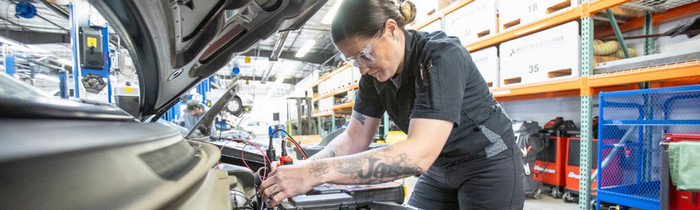 Butte College Automotive Studies female student works on a car battery