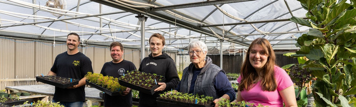 Butte College horticulture students hold up boxes of seedlings
