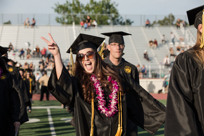 excited-graduate-flashes-peace-sign-at-commencement