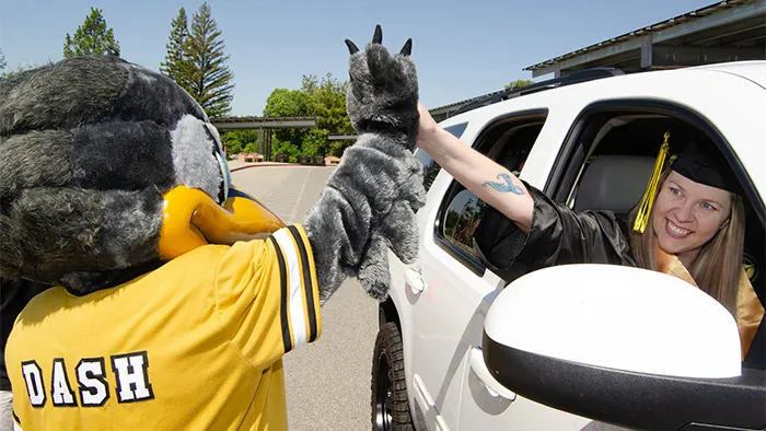 Butte College Graduate give Dash Mascot high five from white vehicle