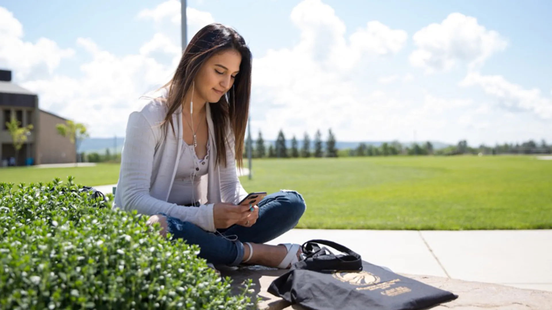 Student on mobile phone relaxes on campus